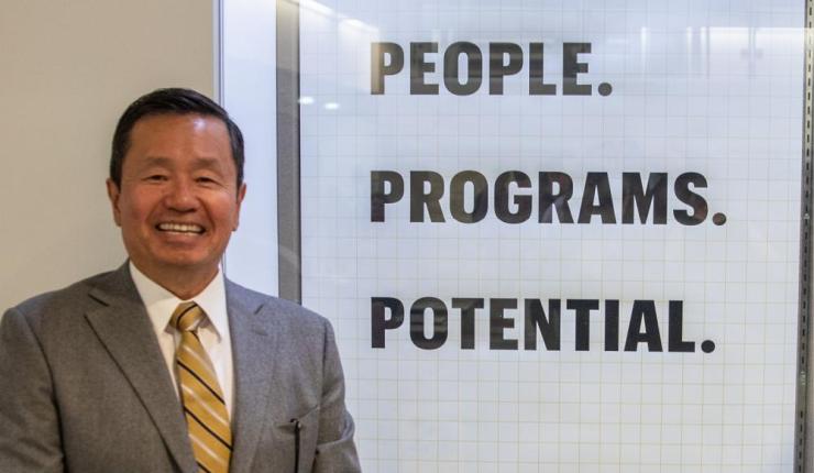 President Choi stands next to a Mizzou Forward banner that reads "People. Programs. Potential."